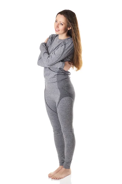 Woman staying and hugging herself with her arms in gray sports thermal underwear. — Stock Photo, Image