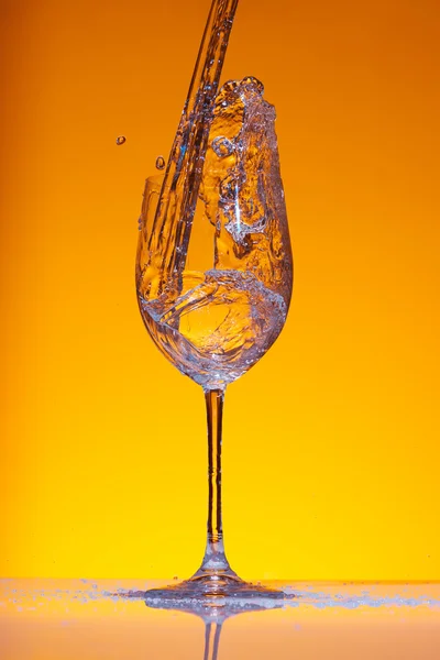 Caída de flujo de agua en la copa de vino creando salpicaduras y remolinos . — Foto de Stock