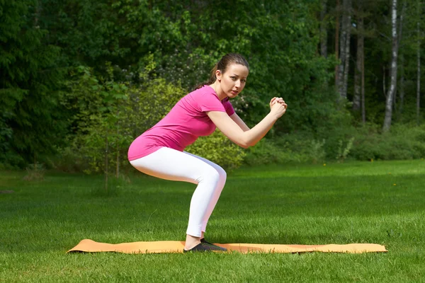 Attrayant brun femme cheveux entraînement fesses et jambes muscles dans squat . — Photo