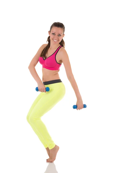 Mulher morena bonita sorridente em esportes néon amarelo leggings e sutiã rosa fazendo exercícios complexos para músculos das costas, pernas, nádegas e mãos usando halteres azuis . — Fotografia de Stock