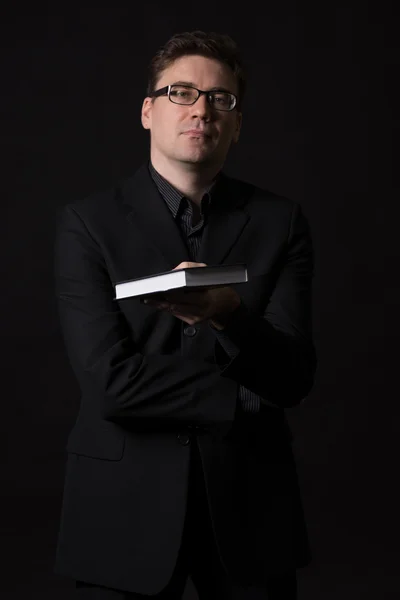 Mand iført et sort jakkesæt præsenterer en bog at læse - Stock-foto