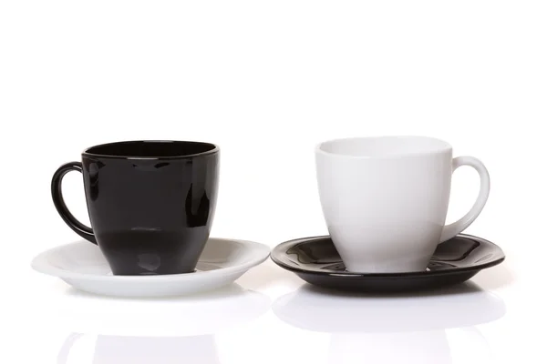 Taza negra en el plato blanco y taza blanca en el plato negro . —  Fotos de Stock