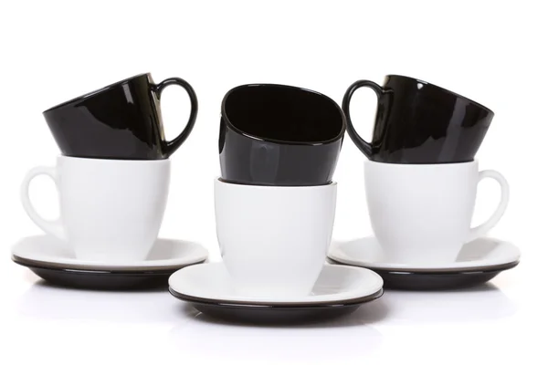 Negro sobre tazas blancas con placas de pila sobre blanco . —  Fotos de Stock