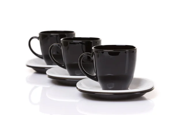 Three black cups on stack of the plates. — Stock Photo, Image