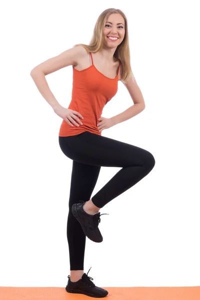 Lachende vrouw in sportkleding opleiding benen op een mat. — Stockfoto