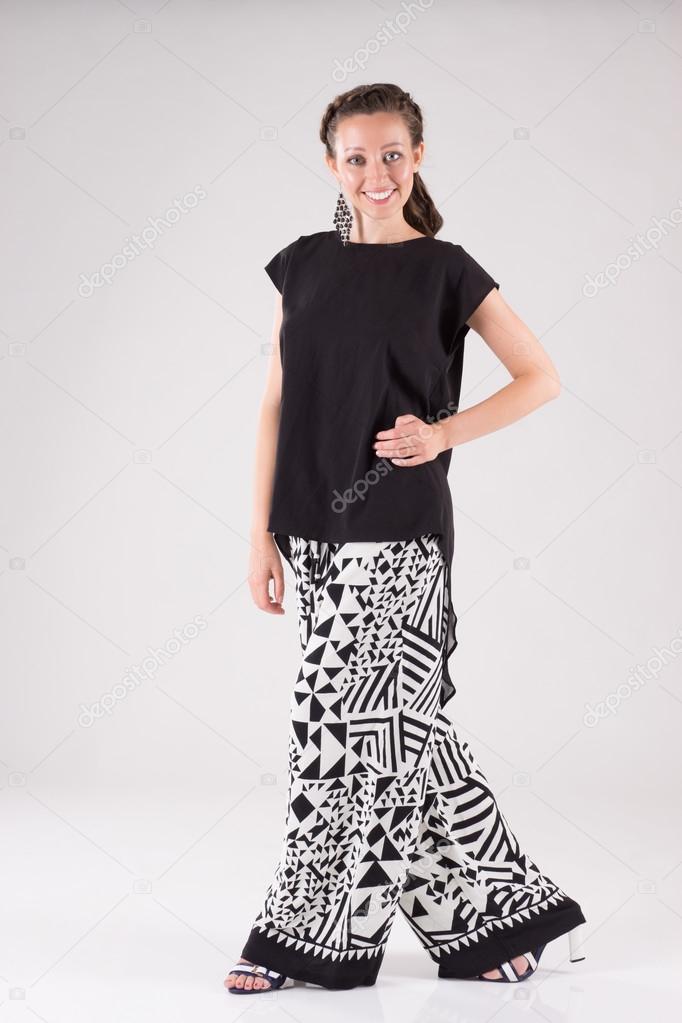Attractive smiling business woman with day make-up dressed in wide black and white trousers and black blouse and high-heeled shoes for walks and meetings.