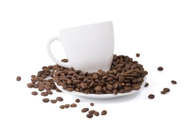 Beyaz fincan kavrulmuş kahve çekirdekleri ile dolu beyaz bir plaka üzerinde.