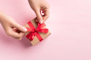 Kadın eli kırmızı kurdeleyle süslenmiş kağıt hediye kutusu, özel gün için hediye paketi, Top view
