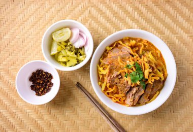 Kuzey Tayland yemeği (Khao Soi), baharatlı körili şehriye çorbası ve turşulu hardal, arpacık soğanı, limon ve yağda kızartılmış kırmızı biber.