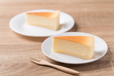 Beyaz tabakta çatallı vanilyalı cheesecake dilimi.