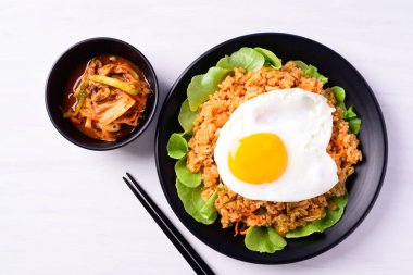 Kızarmış kimchi pilavı, üstünde yumurta ve beyaz arka planda taze kimchi lahanası Kore yemeği, Top View.