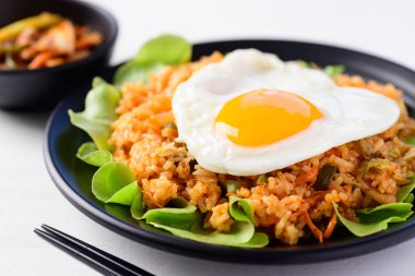 Kızarmış kimchi pilavı, üstünde yumurta ve taze kimçi lahanası, Kore yemeği.