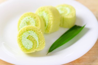 Beyaz tabak üzerinde pandan yaprağı olan dilimlenmiş pandan pastası.