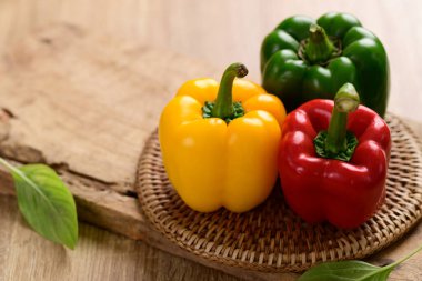 Tahta arka planda taze sarı, kırmızı ve yeşil dolma biber, organik sebze.