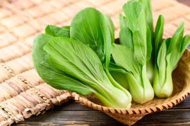 Tahta arka planda bambu sepeti içinde taze Bok Choy veya Pak Choi (Çin lahanası), organik sebzeler