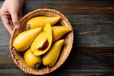 Tahta masada elle tutulan yumurta meyvesi ya da teneke kutu, Tayland meyvesi Xiantao, Lamut Khamen ya da Mon Khai gibi Tayland isimleriyle.