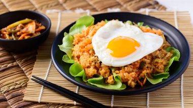 Kızarmış kimchi pilavı, üstünde yumurta ve taze kimçi lahanası, Kore yemeği.