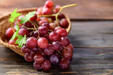 Tahta arka planda sepetteki taze kırmızı üzümler.