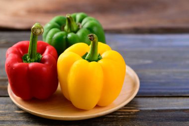 Tahta arka planda taze sarı, kırmızı ve yeşil dolma biber, organik sebzeler.