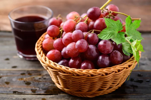 Fruta Fresca Uvas Vermelhas Uma Cesta Suco Fundo Madeira — Fotografia de Stock