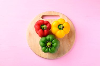 Ahşap kesme tahtasındaki sarı, kırmızı ve yeşil dolma biberler.