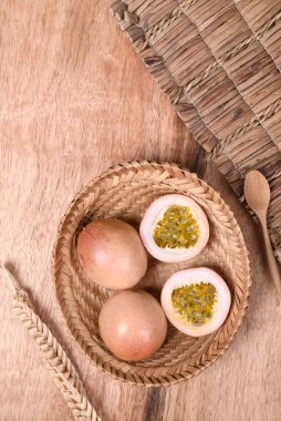 Tahta zemin üzerinde kaşık olan sepetteki taze tutku meyvesi, tropikal meyve, üst manzara.