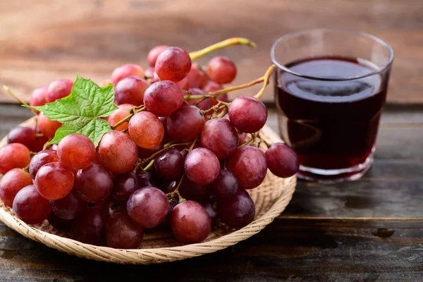 Fruta Fresca Uvas Vermelhas Uma Cesta Suco Fundo Madeira — Fotografia de Stock