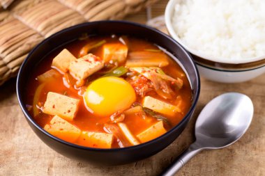 Korean food, Kimchi soup with fofu and egg eating with cooked rice on wooden background clipart