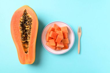 Pastel arka planda yemeye hazır çatalla dilimlenmiş olgun papaya meyvesi, tropikal meyve, Top view