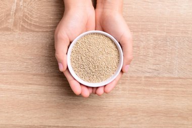 Kahverengi kinoa tohumları ahşap arka planda elle tutulan bir kasede, Üst Manzara