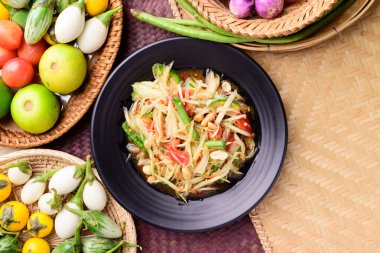 Tayland yemeği (Som tum), baharatlı yeşil papaya salatası dokuma bambu arka planında sebzeler, Top view