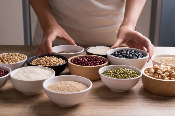 Various cereal grain in a bowl with hand on wooden table preparing for cooking, Food ingredients