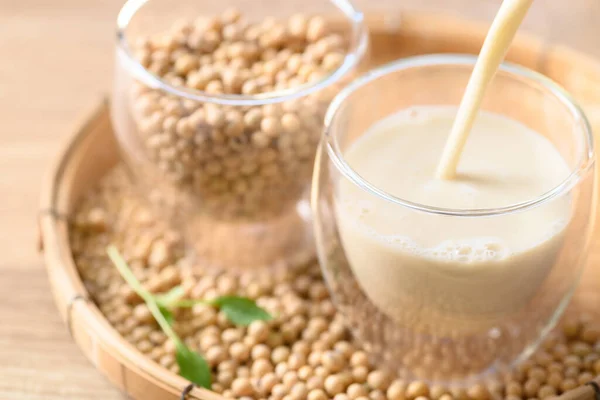 Soy milk pouring into a glass with soybeans on bamboo tray, Healthy drink