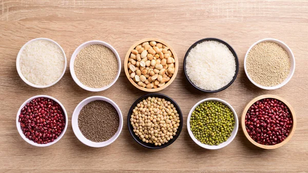 Various cereal grain in a bowl on wooden background (quinoa seeds, peanut, perilla seeds, soybean, azuki beans, rice grain and mung beans)