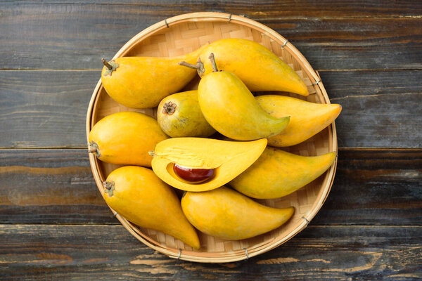 Eggfruit or canistel in a bamboo tray on wooden table, Thai fruit, In Thai names such as Xiantao, Lamut Khamen or Mon khai