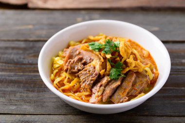 Kuzey Tayland yemekleri (Khao Soi), ahşap arka planda sığır etli baharatlı körili şehriye çorbası.