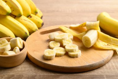 Tahta kesme tahtasının üzerinde dilimlenmiş olgun muz meyvesi pişirmeye hazırlanıyor.