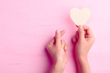 Kalp şeklini koruyan ve pembe arka planda minik kalp şeklini gösteren Sevgililer Günü.