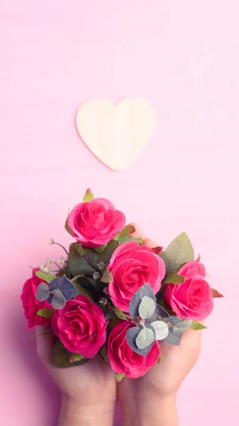 ピンクの背景にハート型の赤いバラの花の花束を手に持って バレンタインデー — ストック写真