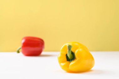 Fresh yellow and red bell pepper on white and yellow background
