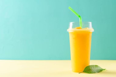 Renkli bir bardakta taze mango smoothie, tropik bir içecek.