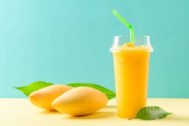 Bardakta taze mango püresi ve renkli mango meyvesi, tropikal içecek.