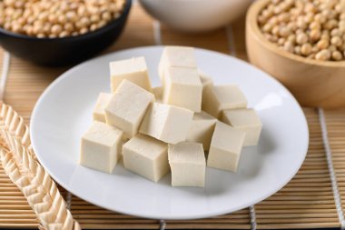 Beyaz tabak ve soya çekirdekli dilimlenmiş tofu, sağlıklı vejetaryen yemeği.
