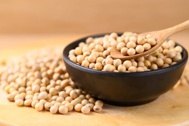 Siyah kasede soya tohumları, ahşap arka planda kaşık, yiyecek malzemeleri.