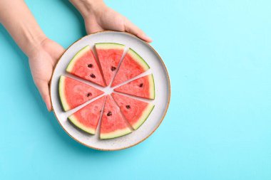 Elle tutulan dilimlenmiş karpuz meyvesi renkli arka plan, tropikal meyve, yaz mevsimi