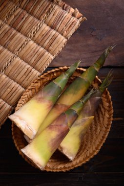 Tahta arka planda bir sepetin içinde taze bambu filizi Asya mutfağında yenilebilir sebze.