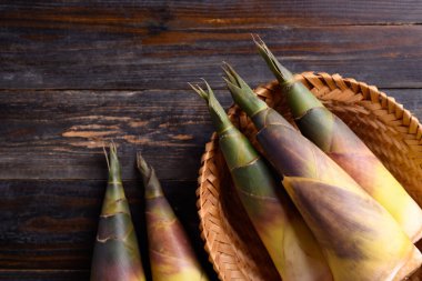Tahta arka planda bir sepetin içinde taze bambu filizi Asya mutfağında yenilebilir sebze.