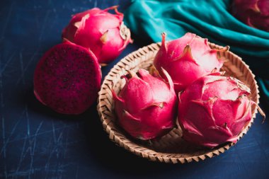Olgun kırmızı ejderha meyvesi ya da pitaya mavi arka planda bambu sepetinde, tropikal meyve