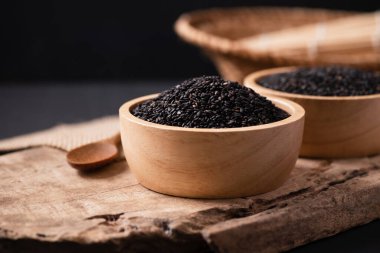 Tahtada kaşık olan bir kasede siyah susam tohumları, natürmort.