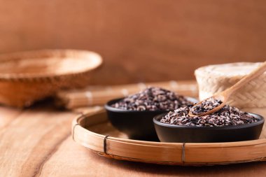 Siyah bir kâsede kaşık ve bambu kabıyla mor glüten pirinç taneleri, Tayland pilavı.